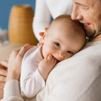 A happy young dad holds his six-month-old son in his arms