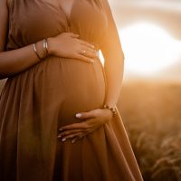 Unrecognizable future mother expecting baby. Health pregnancy, happy motherhood. Pregnant woman touching, caressing belly on wheat natural field background. High quality